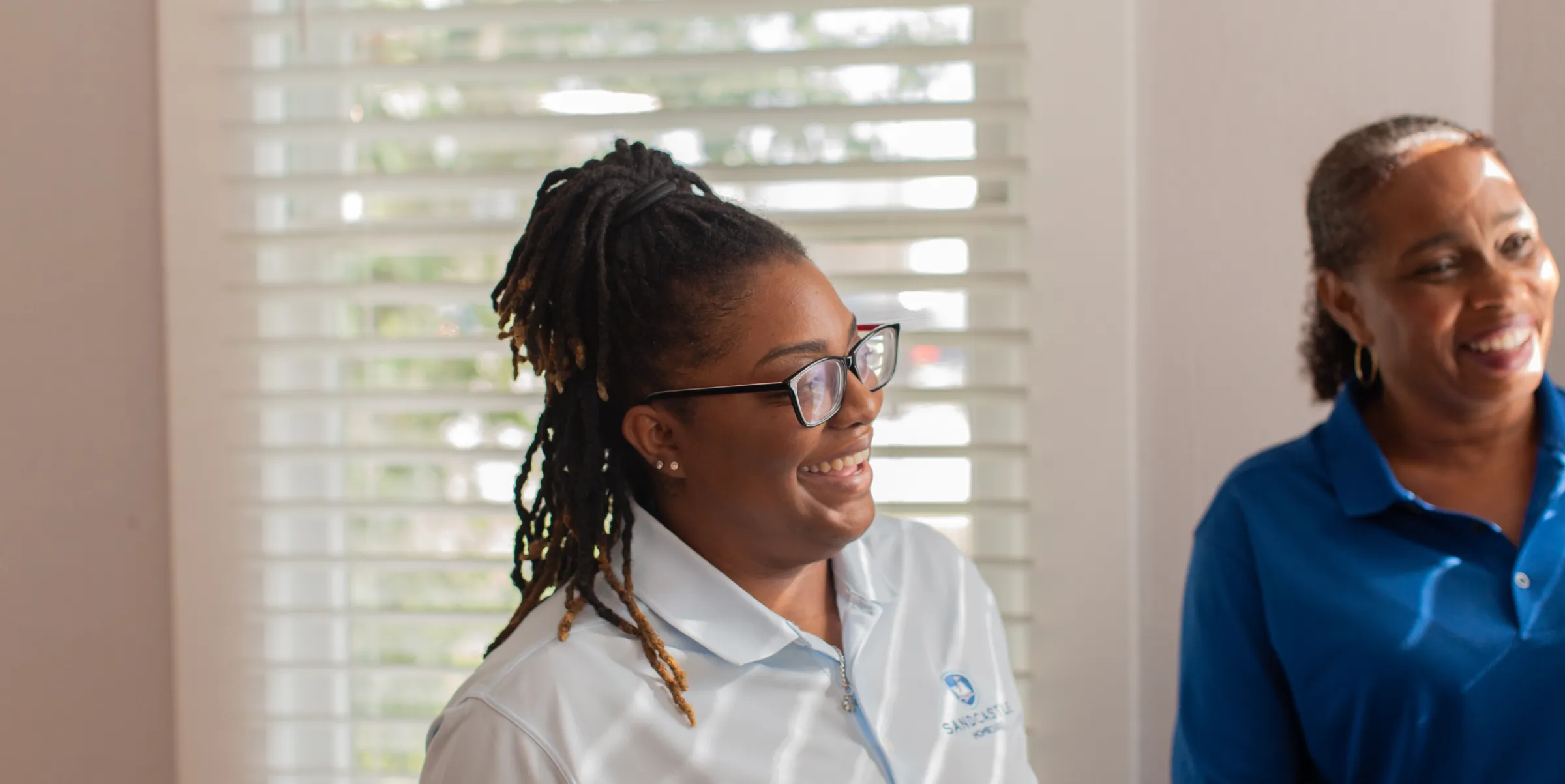 Two smiling Sandcastle caregivers in uniform