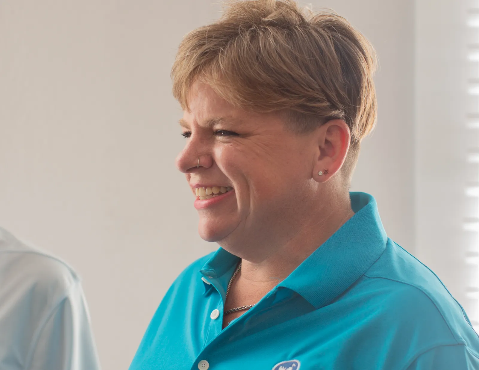 A smiling Sandcastle caregiver in a teal uniform