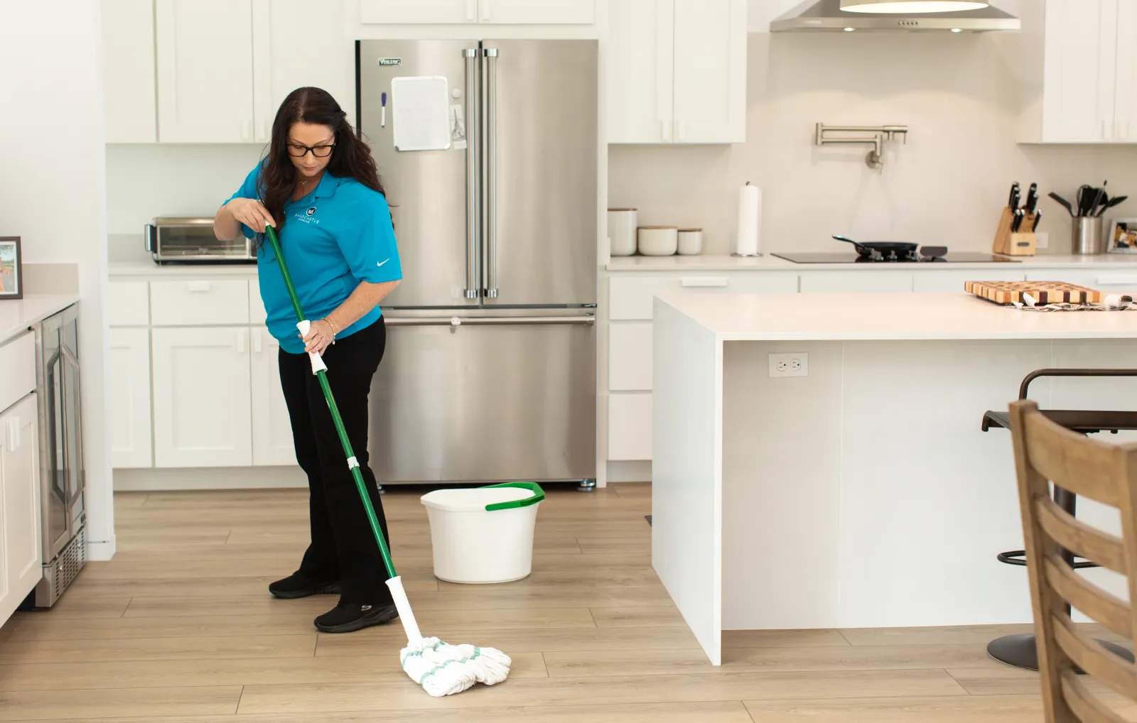 A caregiver mopping a bright kitchen floor