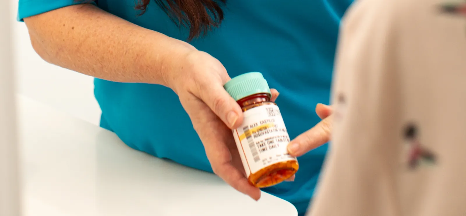 A caregiver handing an older woman her prescription bottle