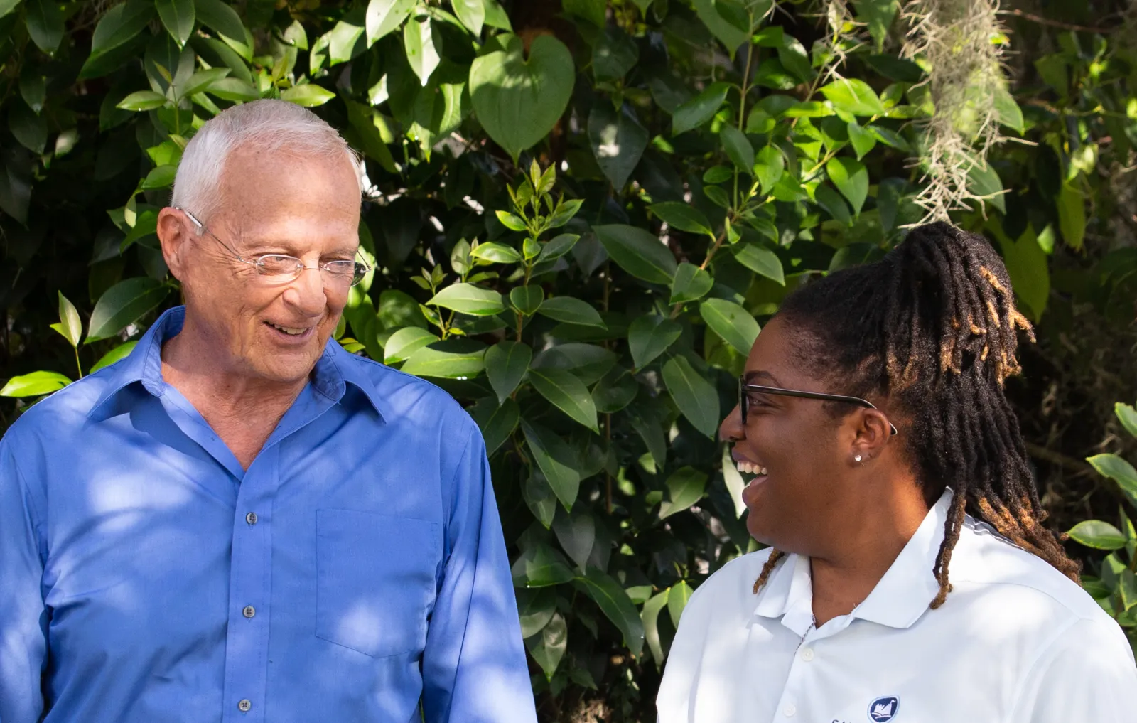 A Sandcastle caregiver laughing with an older man outdoors