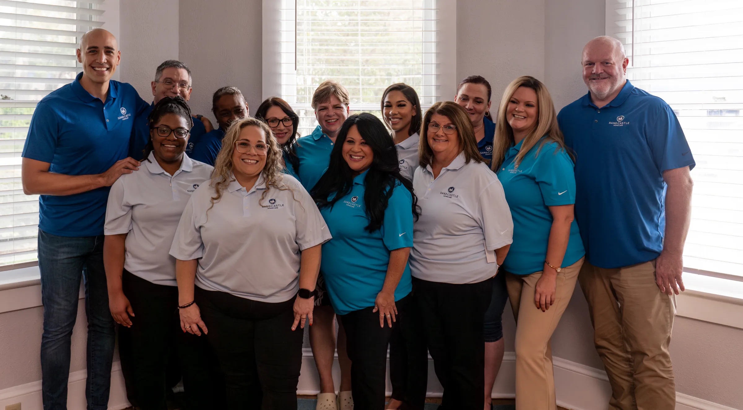 Sandcastle Homecare staff in blue and white uniforms, standing together and smiling