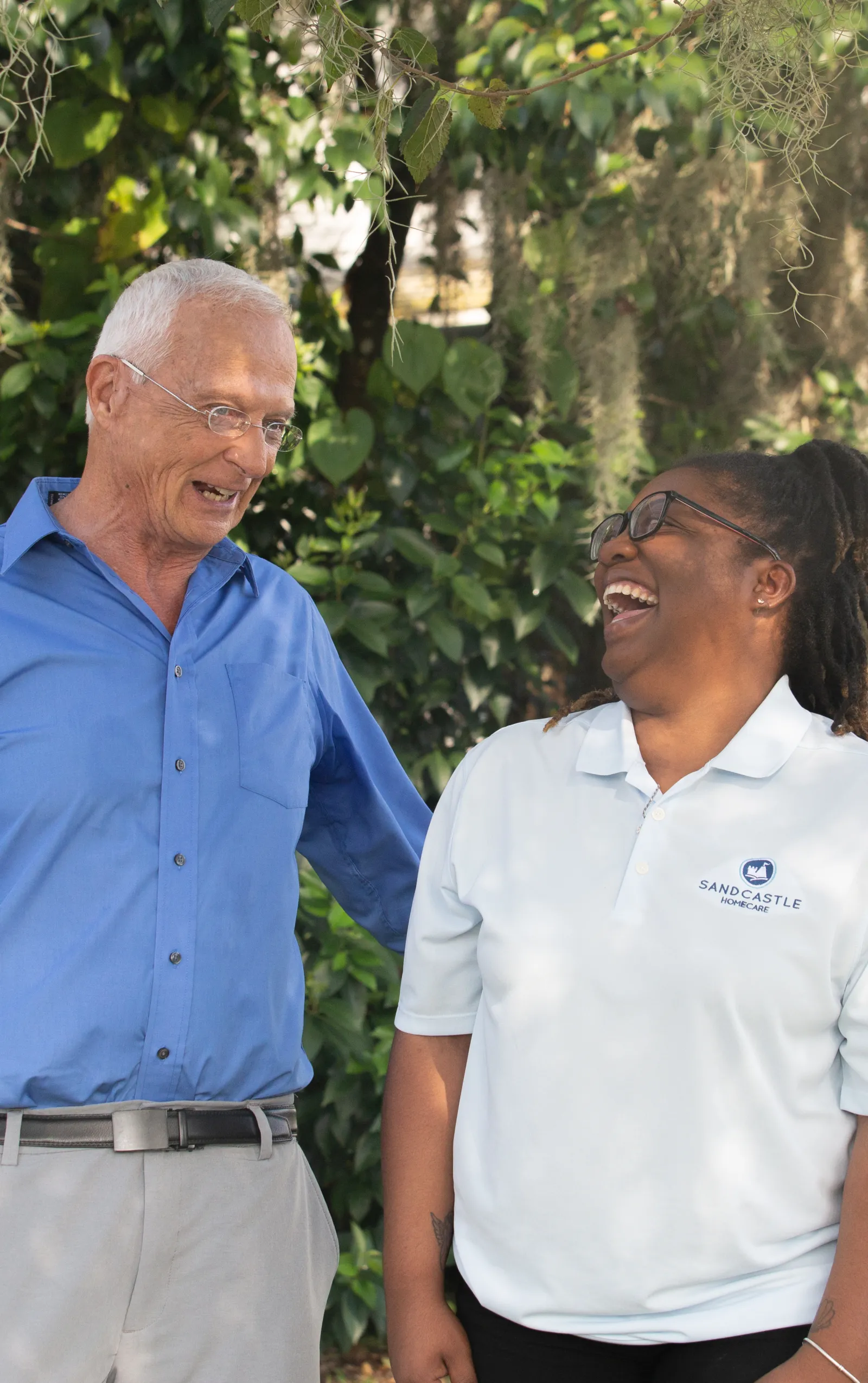 An older man laughing with a young Sandcastle caregiver